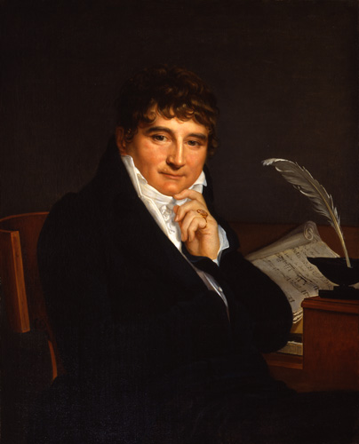 A man with dark brown, slightly curly hair and light skin with rosy cheeks is seated at a desk with his hand to his chin. He wears a black jacket and a white shirt with a tallcollar that reaches his ears and chin, and a ring on his smallest finger.  On the desk behind him, sheet music and a feather pen are positioned for writing.