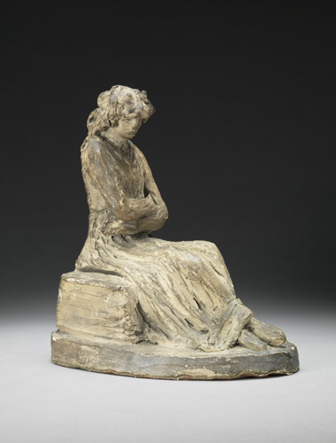 A rough-looking sculpture of a seated woman wearing a dress. She has shoulder-length hair, crossed arms with undetailed hands, and feet crossed at the ankles.