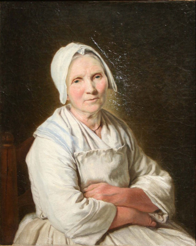 A light-skinned woman with a lined face and gray hair is seated with her arms crossed, looking out at the viewer. She wears a white dress, off-white apron, and white cap.