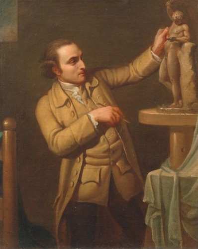 A man with light skin, a hooked nose, and dark blonde hair curled above his ears stands in front of a clay sculpture of a nude man. He appears to be the artist, considering a detail of the sculpture with one hand raised toward it and the other holding a tool. He wears a brown coat and waistcoat.