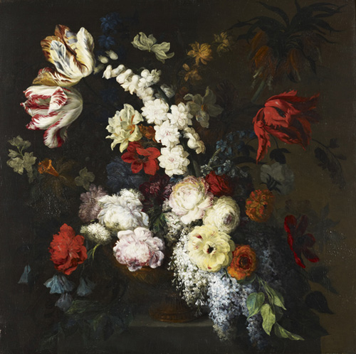 A large grouping of flowers in a vase, with many white and off-white flowers at the center and darker colors like red, orange, and blue toward the edges.