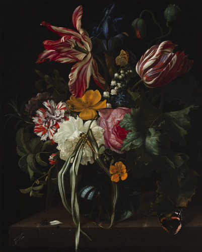 A dark vase contains a small flower arrangement with red-and-white striped flowers, white and pink flowers with ruffled edges, a blue iris, and several small yellow flowers. A dragonfly and a butterfly rest on the flowers, while a second butterfly with orange stripes on its black wings has landed on the edge of the table.