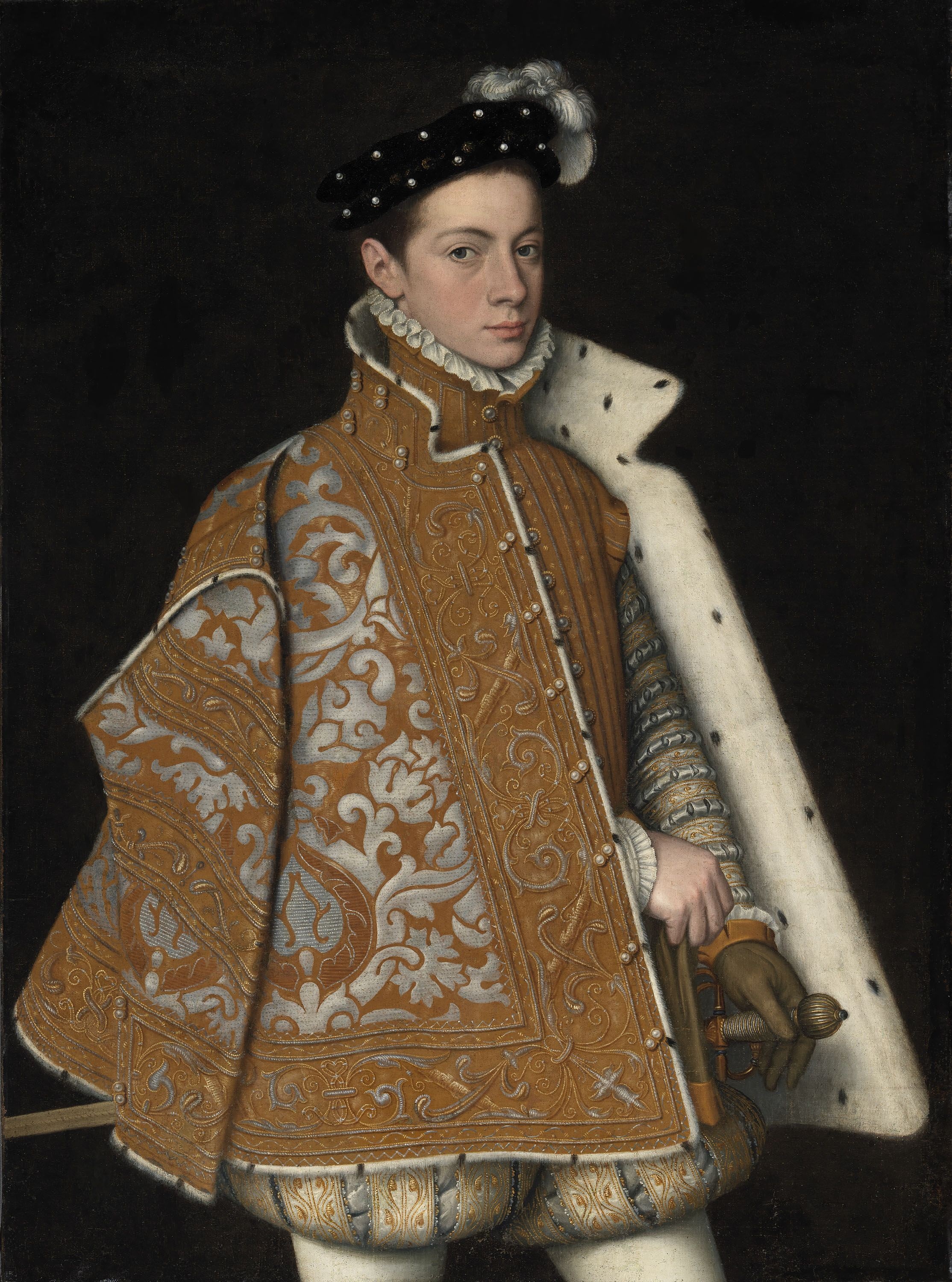 A portrait of a young man against a dark background, cropped at the thighs. He is extravagantly dressed in a brocade cap lined with ermine fir and a black, embellished hat. His left hand is gloved and rests on the sword he has at his hip. He looks at the viewer directly, with confidence.