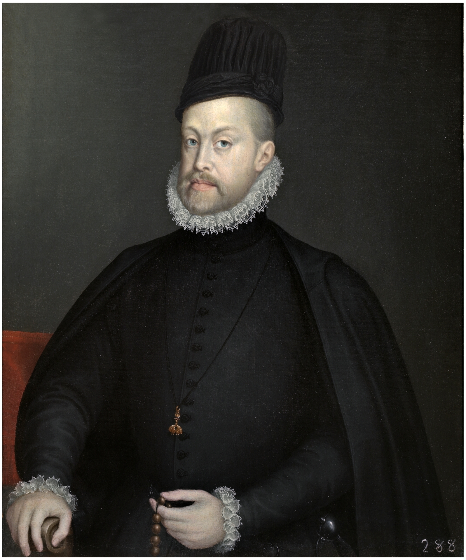 A half-length portrait of a man in a black outfit with white lace at his collar and his sleeves. He is seated on a chair with red behind him. He is wearing a tall, black hat. He holds a rosary in his left hand and looks directly at the viewer.