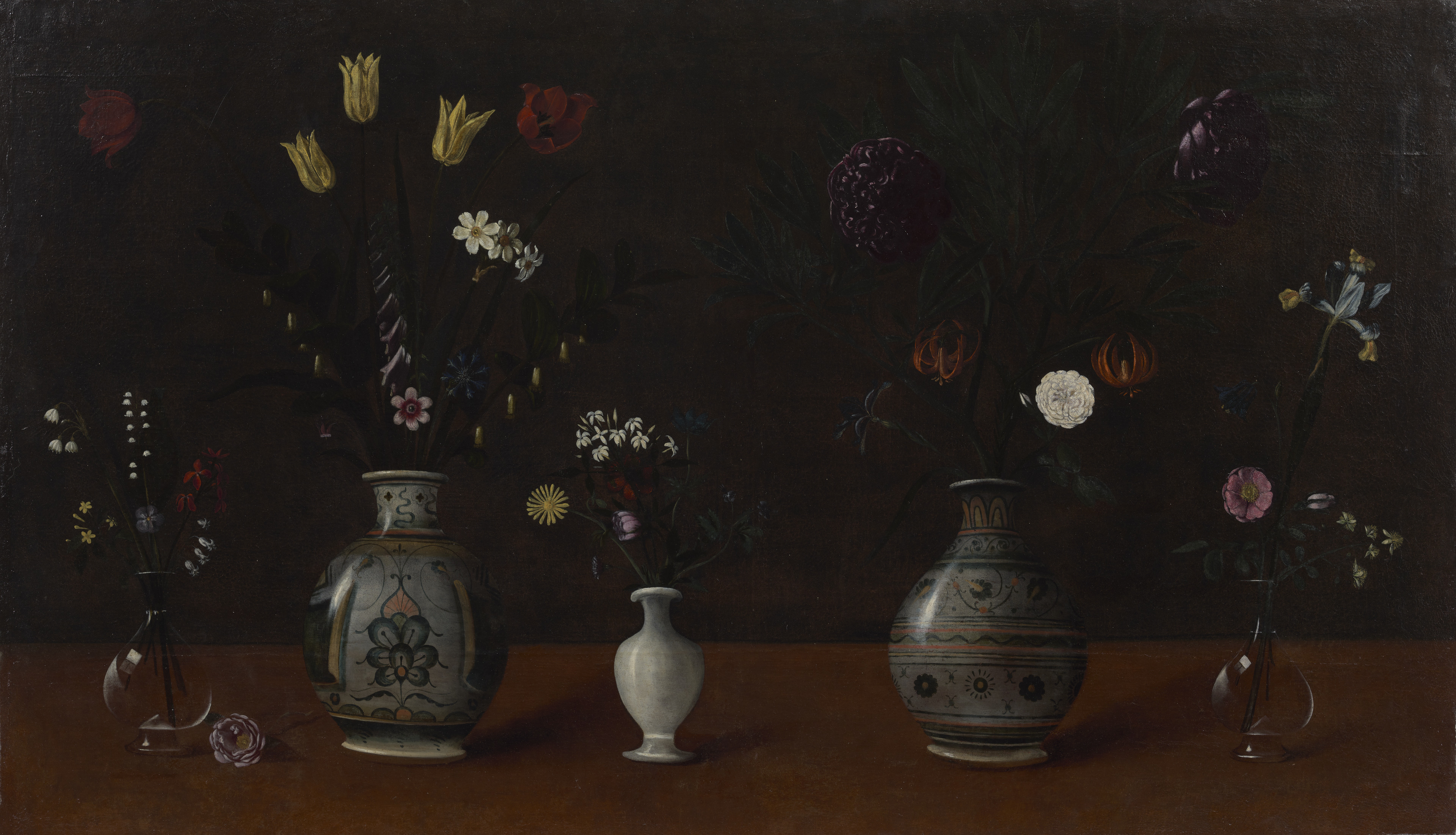 A still life painting of five vases on a table, filled with different flowers. Two of the vases are painted with intricate designs and two are glass; the one at the center is plain white ceramic. There is one light purple flower on the table, next to the glass vase on the left side of the canvas.