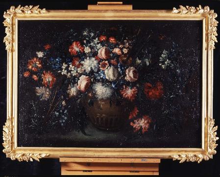 A horizontal-format still life with a brown pot at the center overflowing with flowers of every color. The composition is set against a dark background.