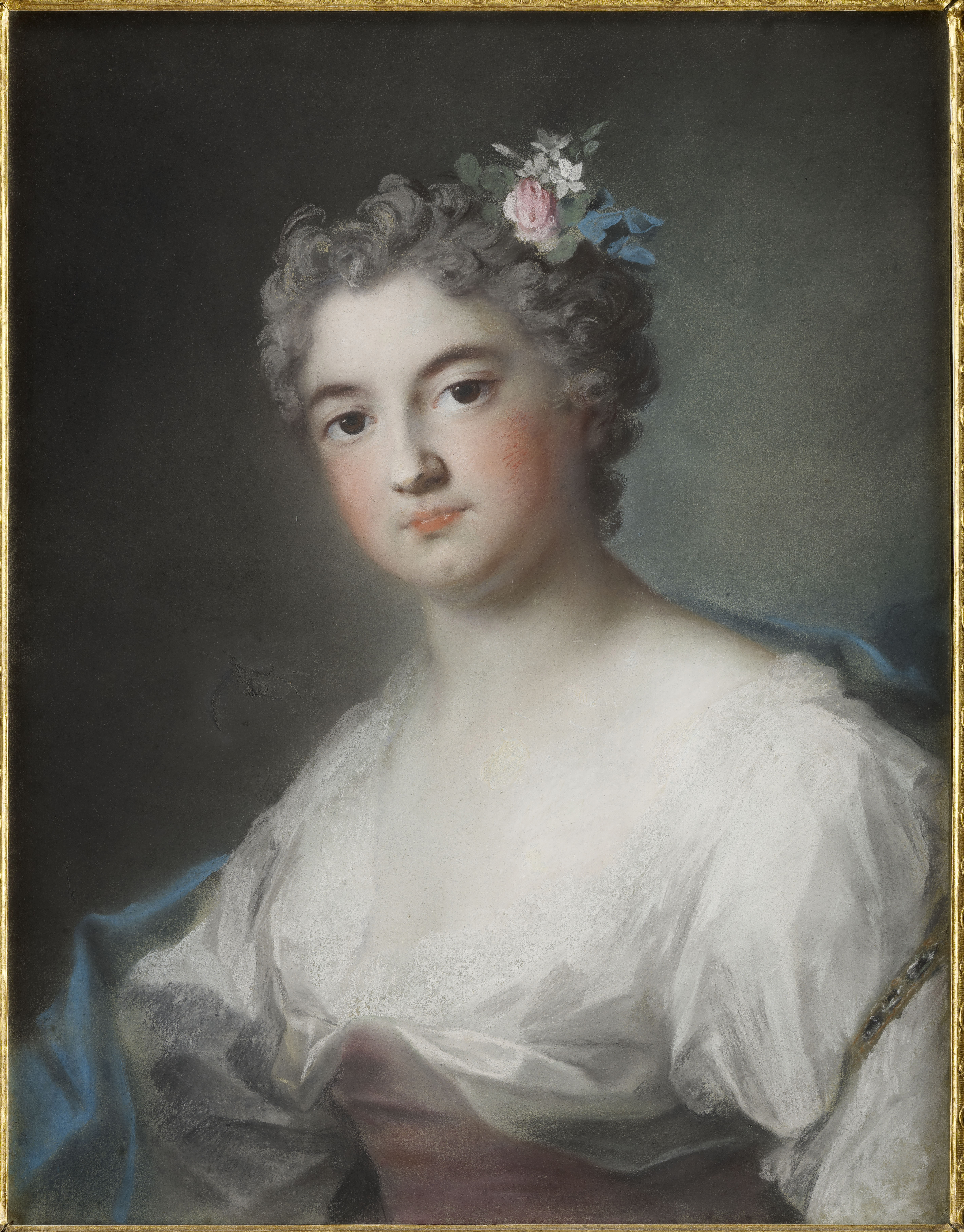 A half-length portrait of a young woman with gray hair, wearing a white and pink gown with a blue shawl around her shoulders. Her cheeks are heavily rouged, and she has flowers in her hair. She looks at the viewer directly with a serious expression. 