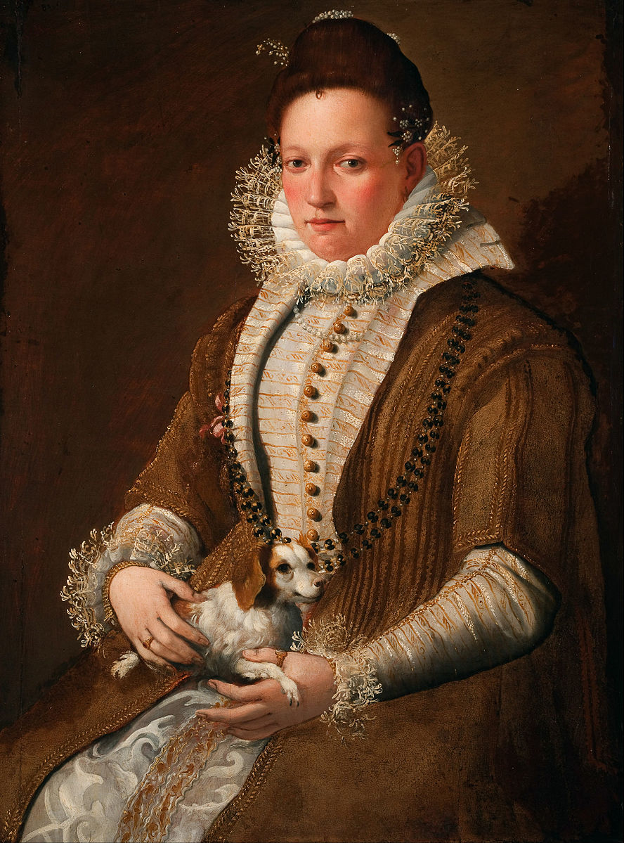 A half-length portrait of a woman in an elaborate dress with ornate details and lace at her collar and her sleeves. The colors of the background and her dress and whites and browns. She holds a small brown and white dog in her lap and looks directly at the viewer.