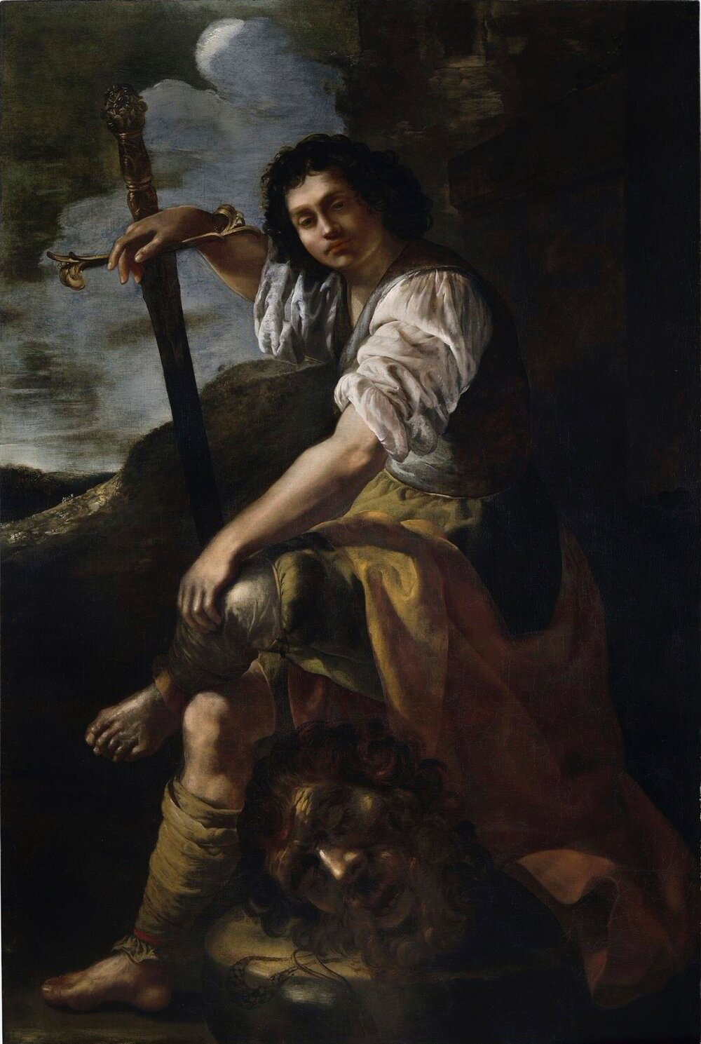 A young man sits on the head of the giant he has killed, with his ankle crossed over his knee. He wears an ambiguous classical costume and rests his right hand on a sword. He looks directly at the viewer with confidence.
