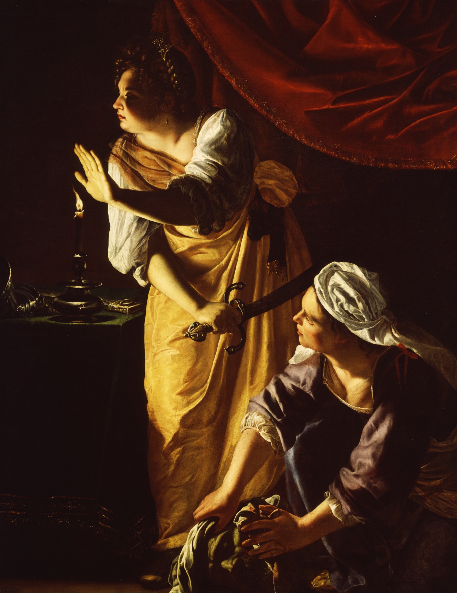 Two women appear in candlelight, their faces partially obscured. The younger woman, in yellow, hold a sword in one hand and holds the other hand up as thought to say “stop.” The older woman crouches down, wearing a purple dress and a white head covering. She uses a cloth to wrap the bloodied head of a man, which has been violently separated from its body. A red velvet cloth is draped behind them, heightening the drama of the moment. 