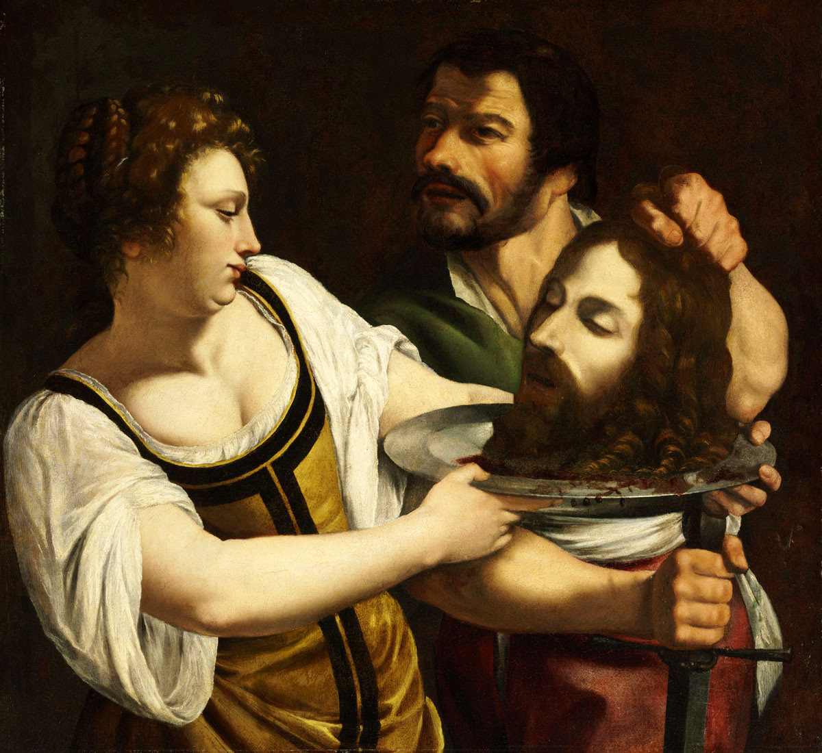 A man and a woman are in conversation. The woman holds a silver platter with the decapitated head of a bearded man on it. The man next to her grabs the head by the hair, lifting it for her to see. He holds a sword pointed down in the other hand. There is no sense of setting.