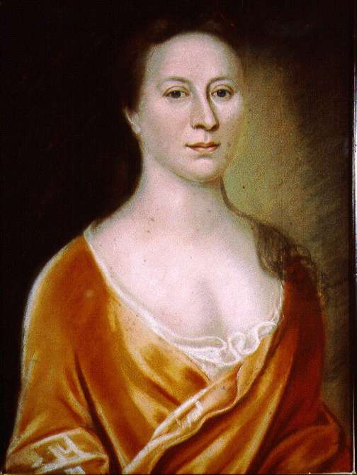 A half-length portrait of a woman, wearing an orange gown that crosses at her bust with a white chemise beneath. Her brown curly hair is pulled back and rests on one shoulder. She looks out directly at the viewer with a neutral expression and a slight smile. 