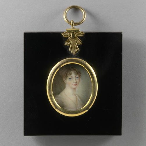 An oval portrait miniature of a young woman looking directly at the viewer with a slight smile. Her curly bangs are parted in the middle, and she has bright blue eyes. She is wearing a cream-colored dress with a long beaded necklace. The portrait is set in a simple gold frame. 