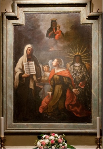 An image of a saint on her knees, looking up at a figure who holds an open book in front of her. Above the figures, in the clouds, the Virgin Mary appears holding the Infant Jesus. Behind the saint, there are two figures: an angel and another figure. The painting is set in an architectural frame as part of a church decoration. 