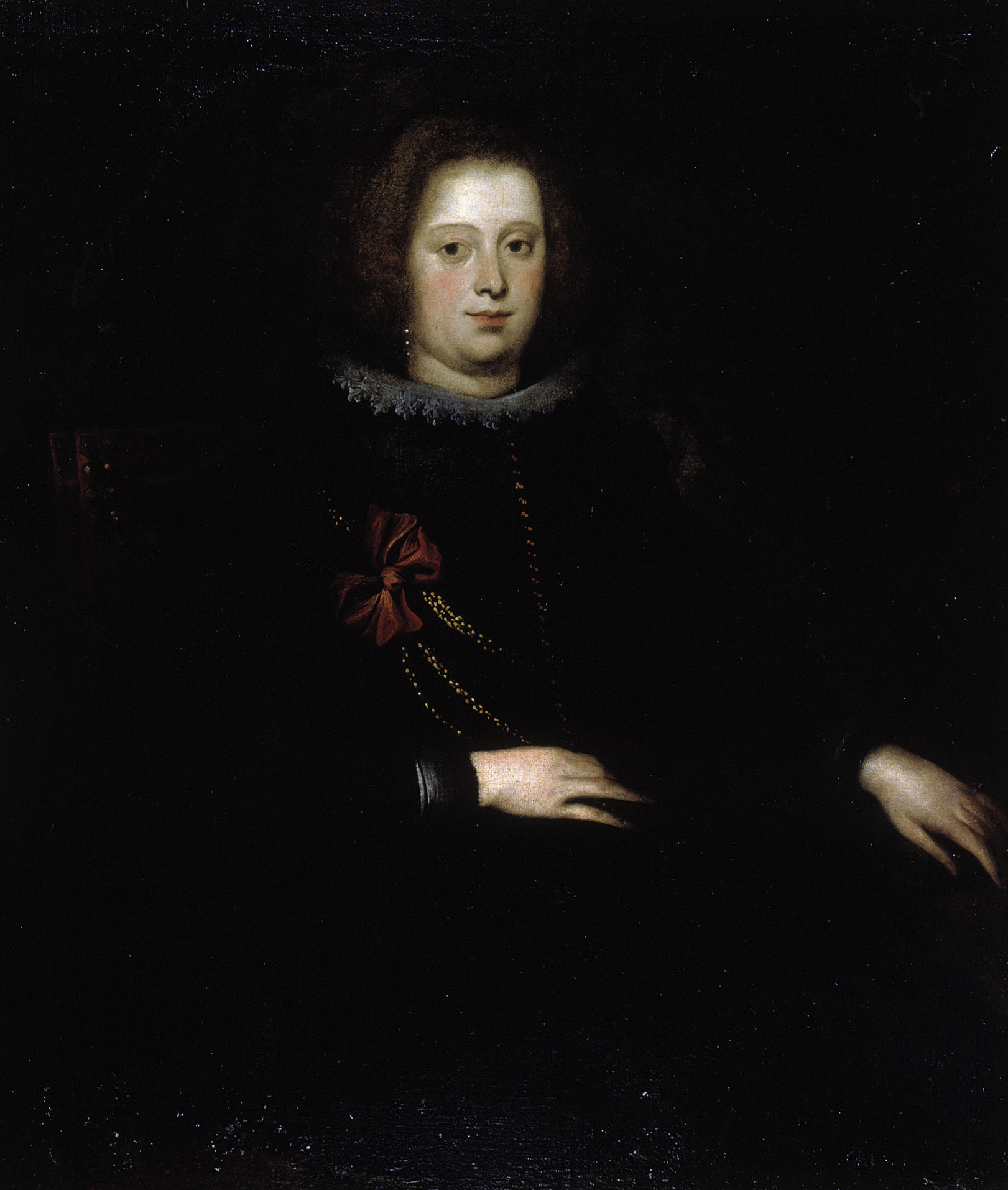 A half-length portrait of a woman dressing black, against a dark background. She has a small white lace collar and some strands of gold cord across her chest, fixed in place with a dark red bow. Her hair is pulled back, and she looks at the viewer with a neutral expression.