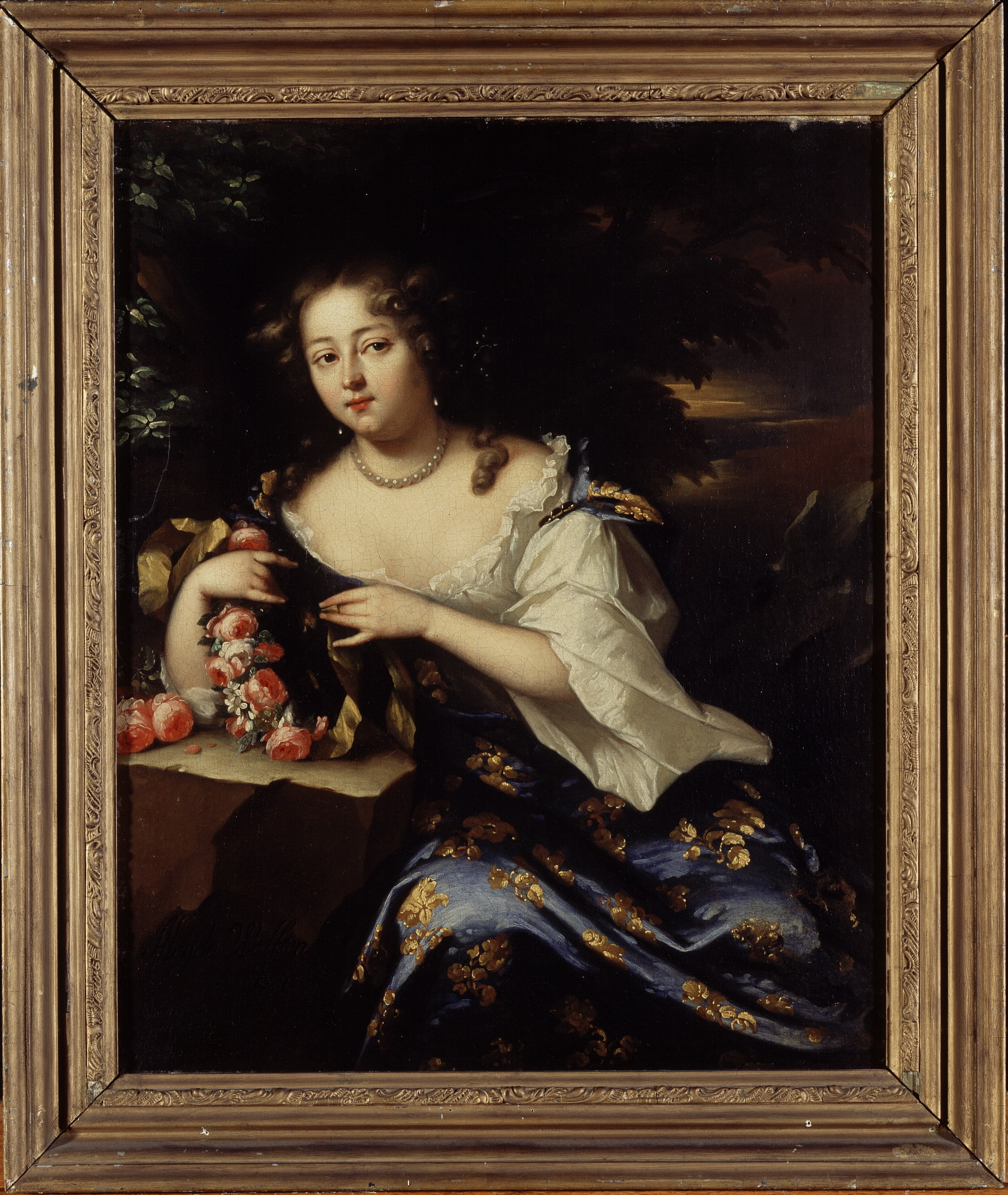 A portrait of a woman facing the viewer but looking off to her right with a slight, skeptical smile. She leans on a rock with her right elbow and holds a wreath of flowers in both hands. She is elegantly dressed and wears a pearl necklace with matching pearl earrings.