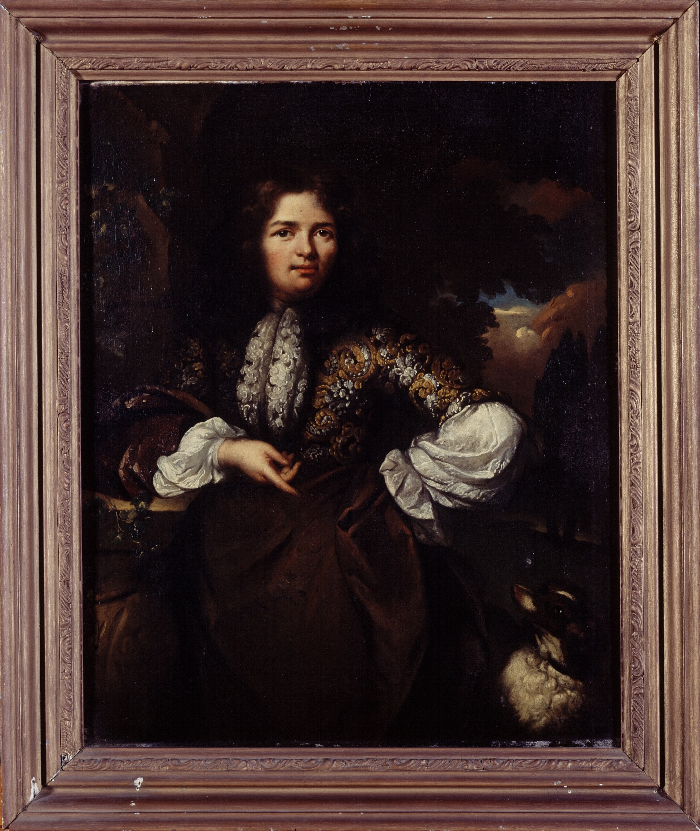 A portrait of a man, elaborately dressed in a seventeenth-century outfit. He is shown at three-quarters length, standing with his right elbow resting on a rock and he looks at the viewer directly with a neutral expression. He rests his left hand at his waist, jutting out his left elbow.  
